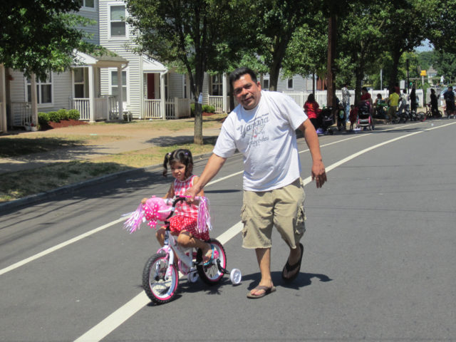 Latino man and child on training bike