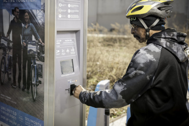 man using bike share kiosk