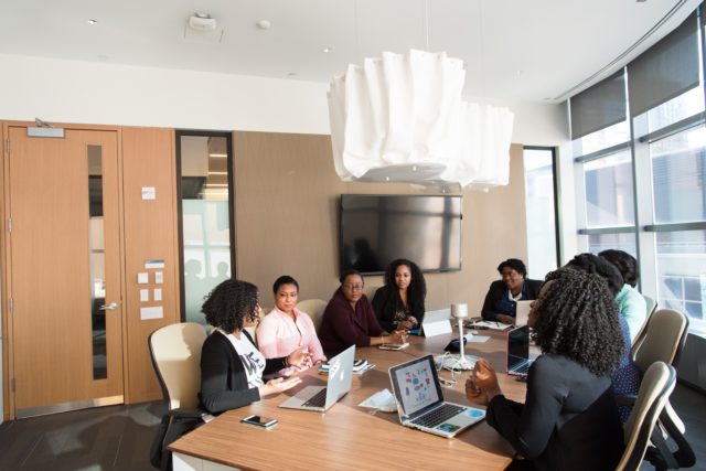 A group of diverse women sit at a desk and work together