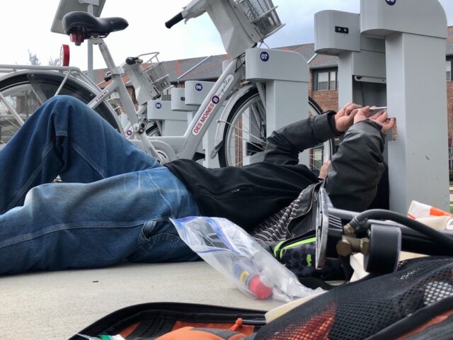 A bike technician uses tool to work on a bike station dock.