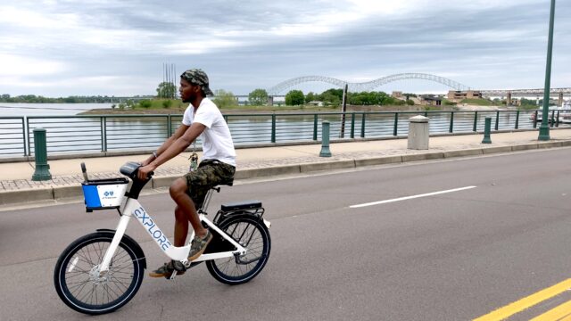 A man rides his bike down an open street