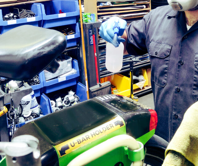 A man uses a spray bottle to sanitize a bike seat