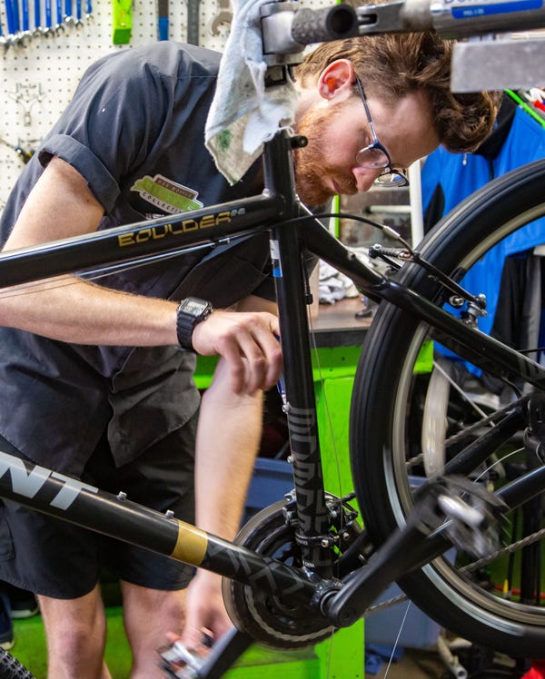 A man works on his bicycle in a shop.